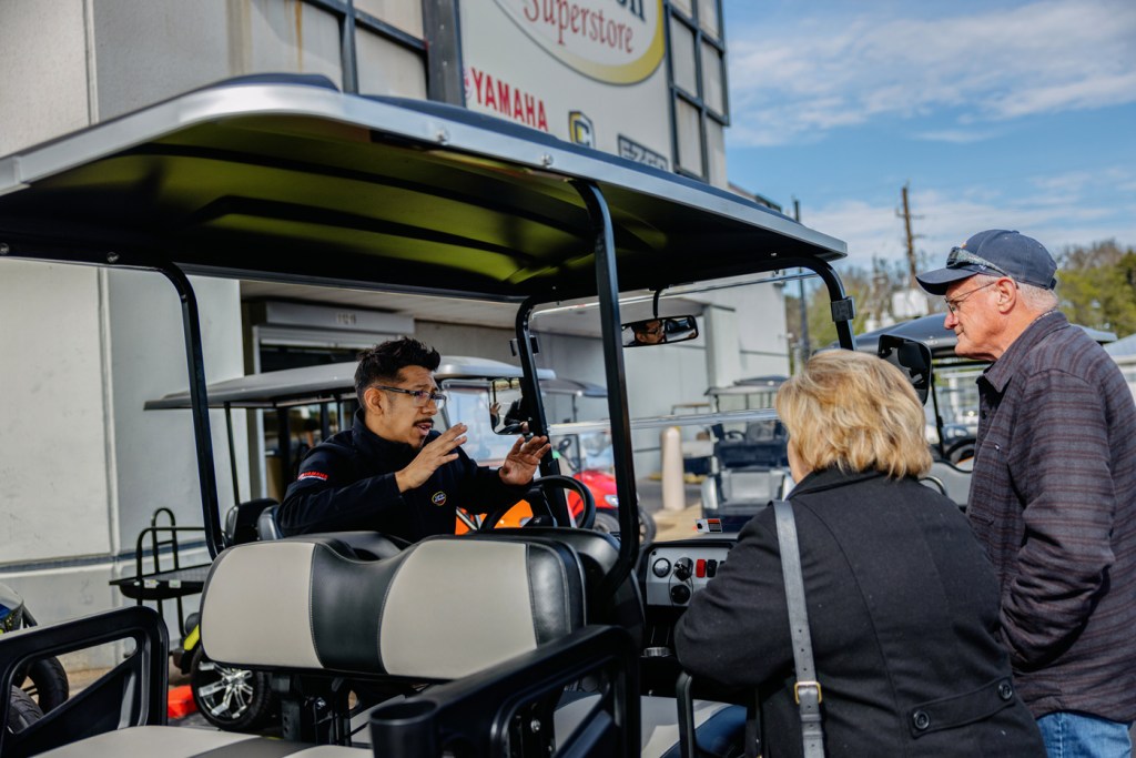 Golf cart sales consultant Abel Barrera talks to customers about golf carts as they shop for one.