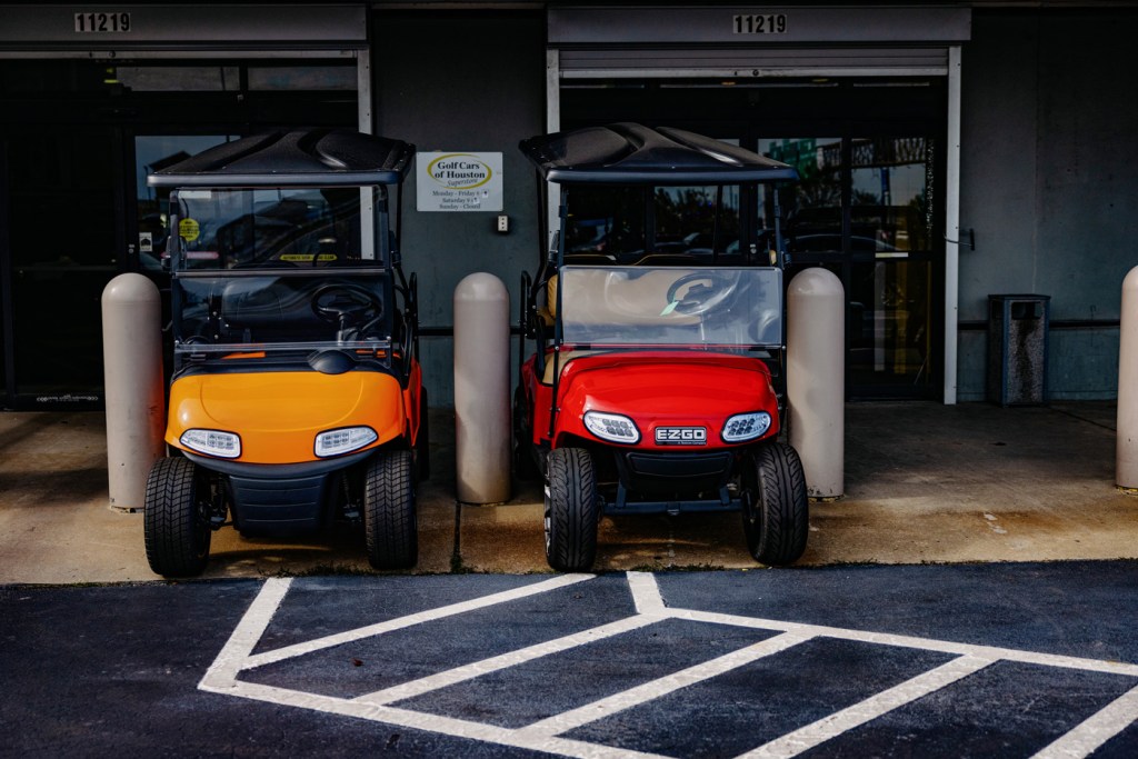 Golf carts painted in bright colors parked by a golf cart shop.