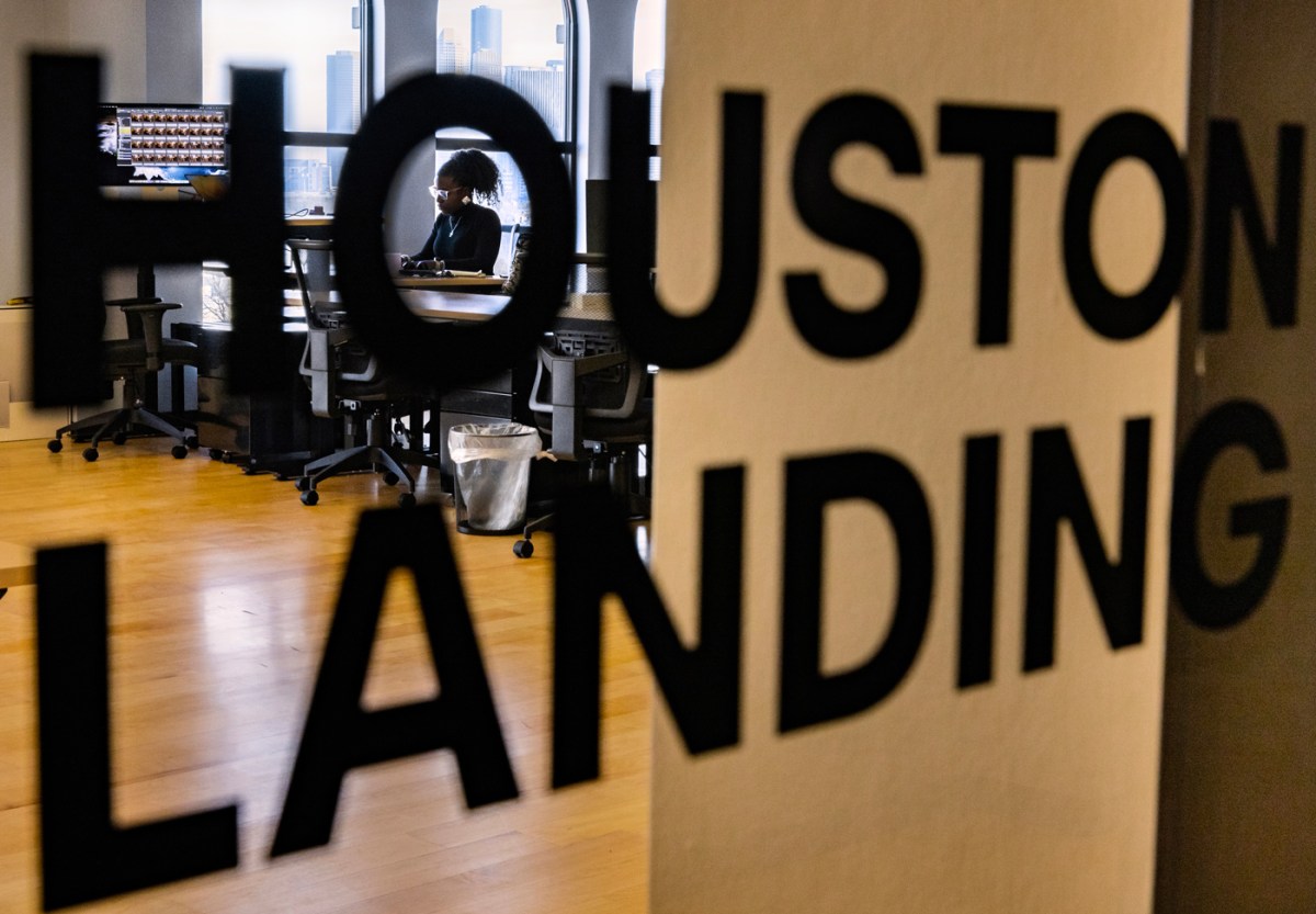 Houston Landing diverse communities reporter Monique Welch is seen through the Houston Landing office entrance sign