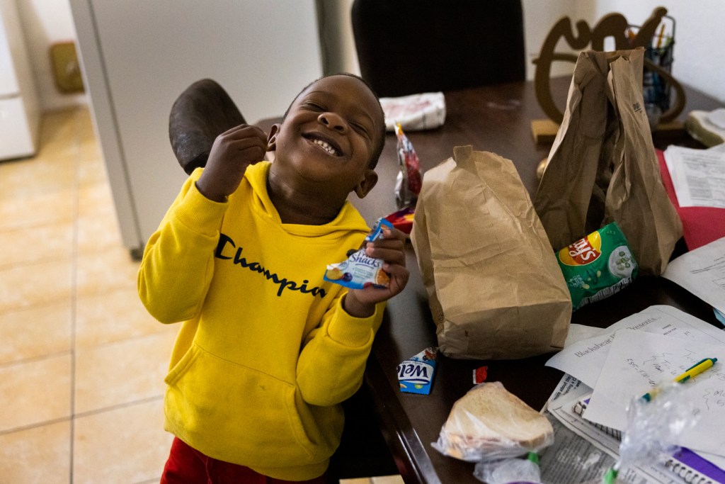 Child smiles after accepting a snack from his mother
