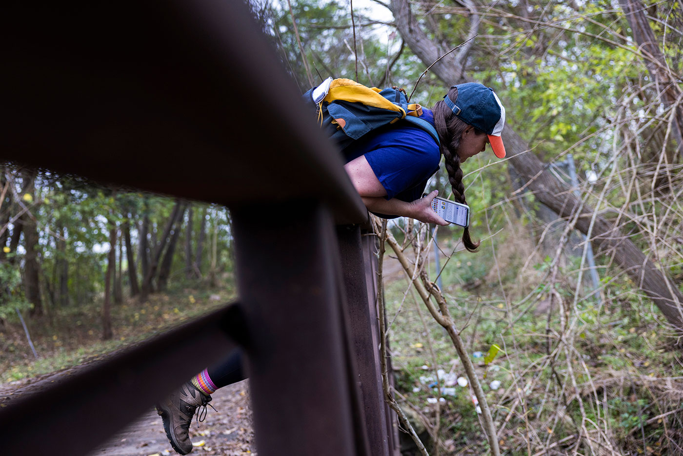 Houston Landing columnist Maggie Gordon leans over a bridge railing as she explores the south bank of the Buffalo Bayou Hike and Bike Trail in Houston.