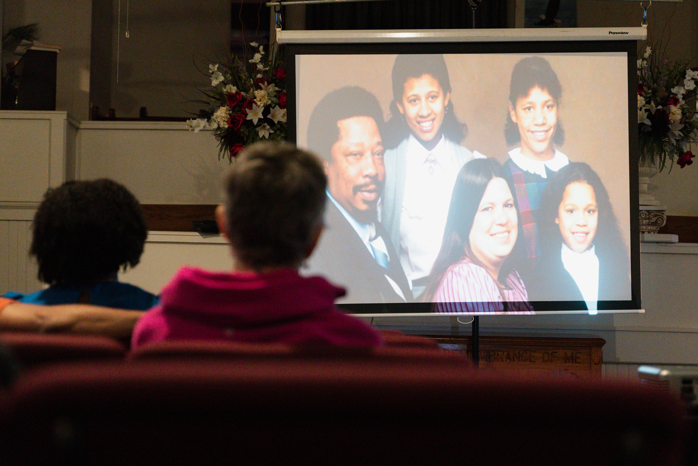 People gather at a church to watch a series about justice and race on a screen.