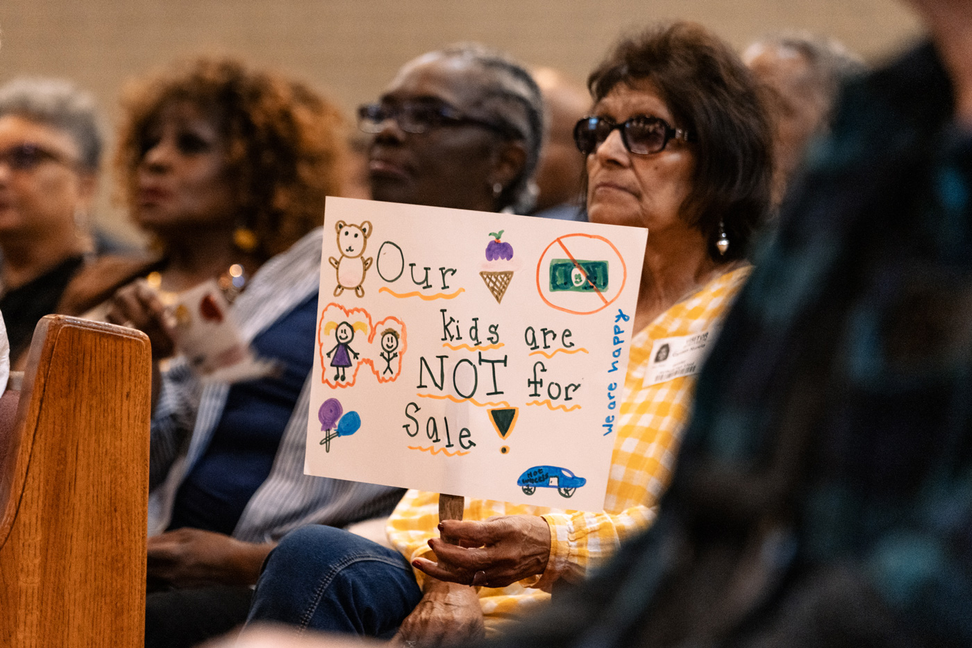 Woman holds a sign protesting goverment agency from taking over a school district.