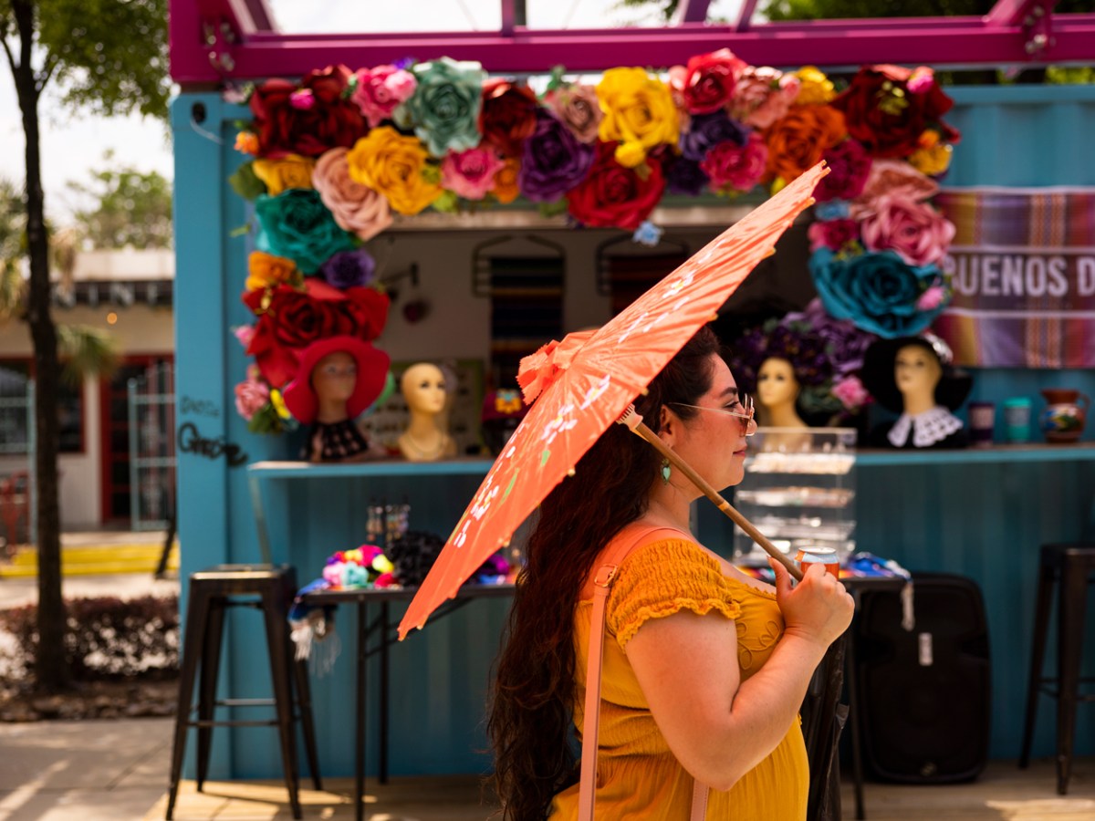 A woman walks by a decorative arrangement of flowers Saturday at the Como La Flor Market in the Esplanade at Navigation