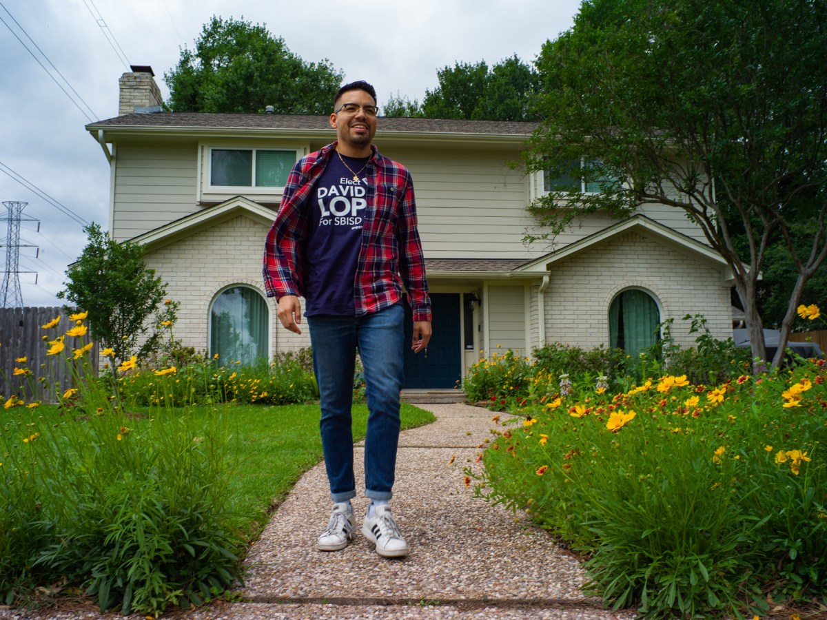 SBISD candidate David Lopez walks outside of a house near flowers