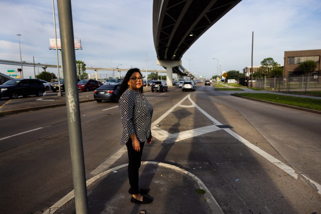A woman waits to cross a street in the morning
