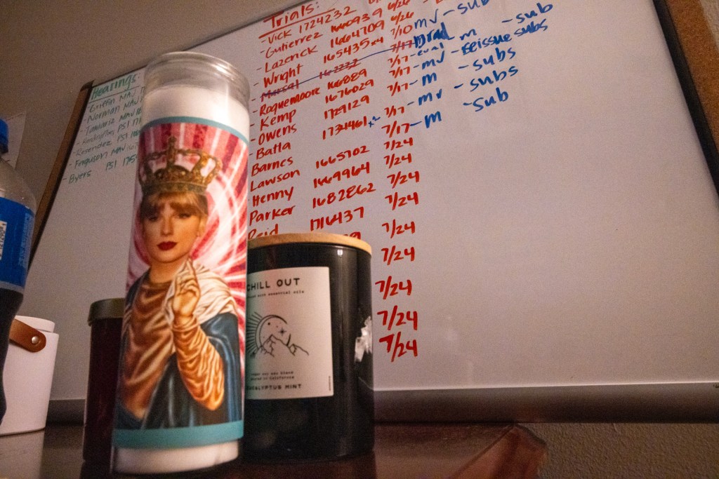 A candle depicting Taylor Swift stands in the foreground while a list of hearings and trails is seen in the background of Nidia Ventura’s office at the Harris County Criminal Justice Center