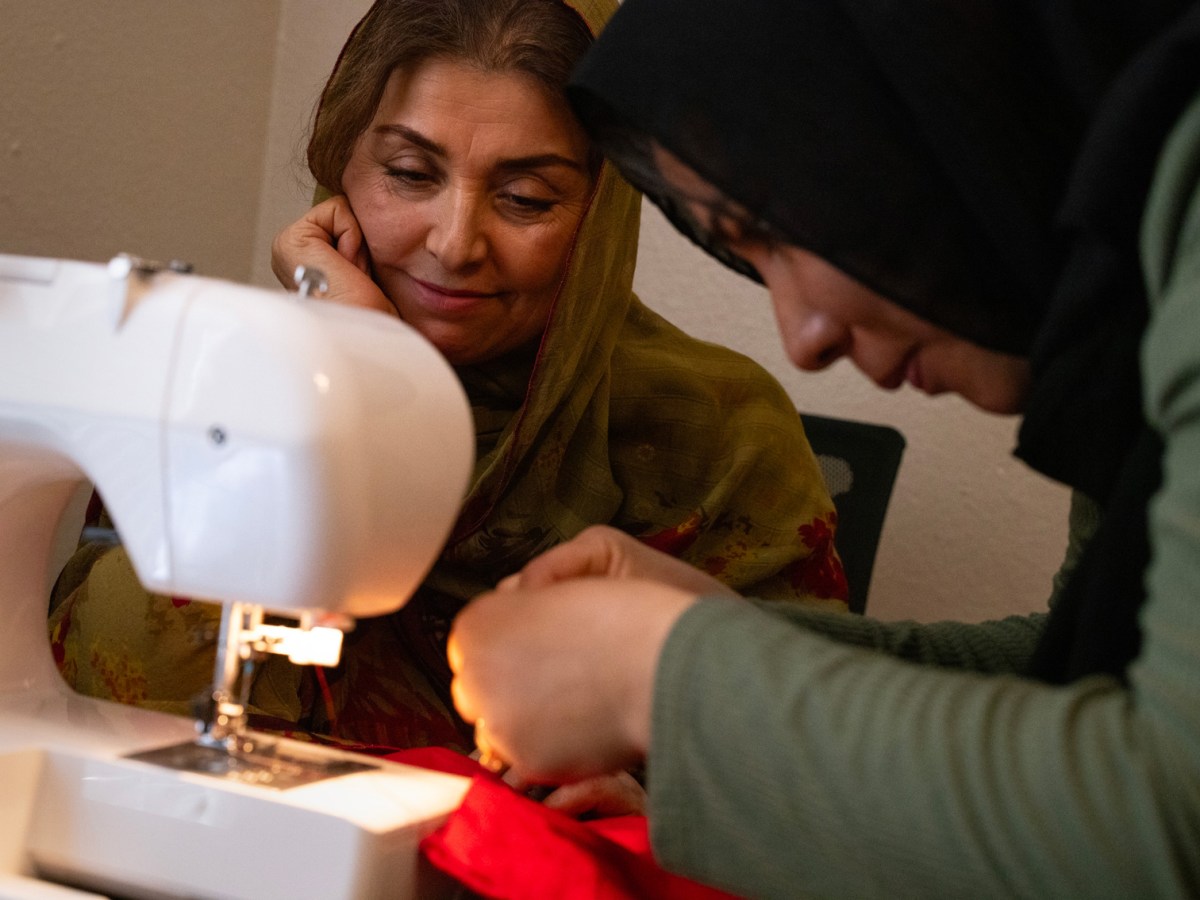 Shukria Barlas, left, watches Masuma Aziz, right, 23, attach thread onto a sewing machine during a sewing class for women