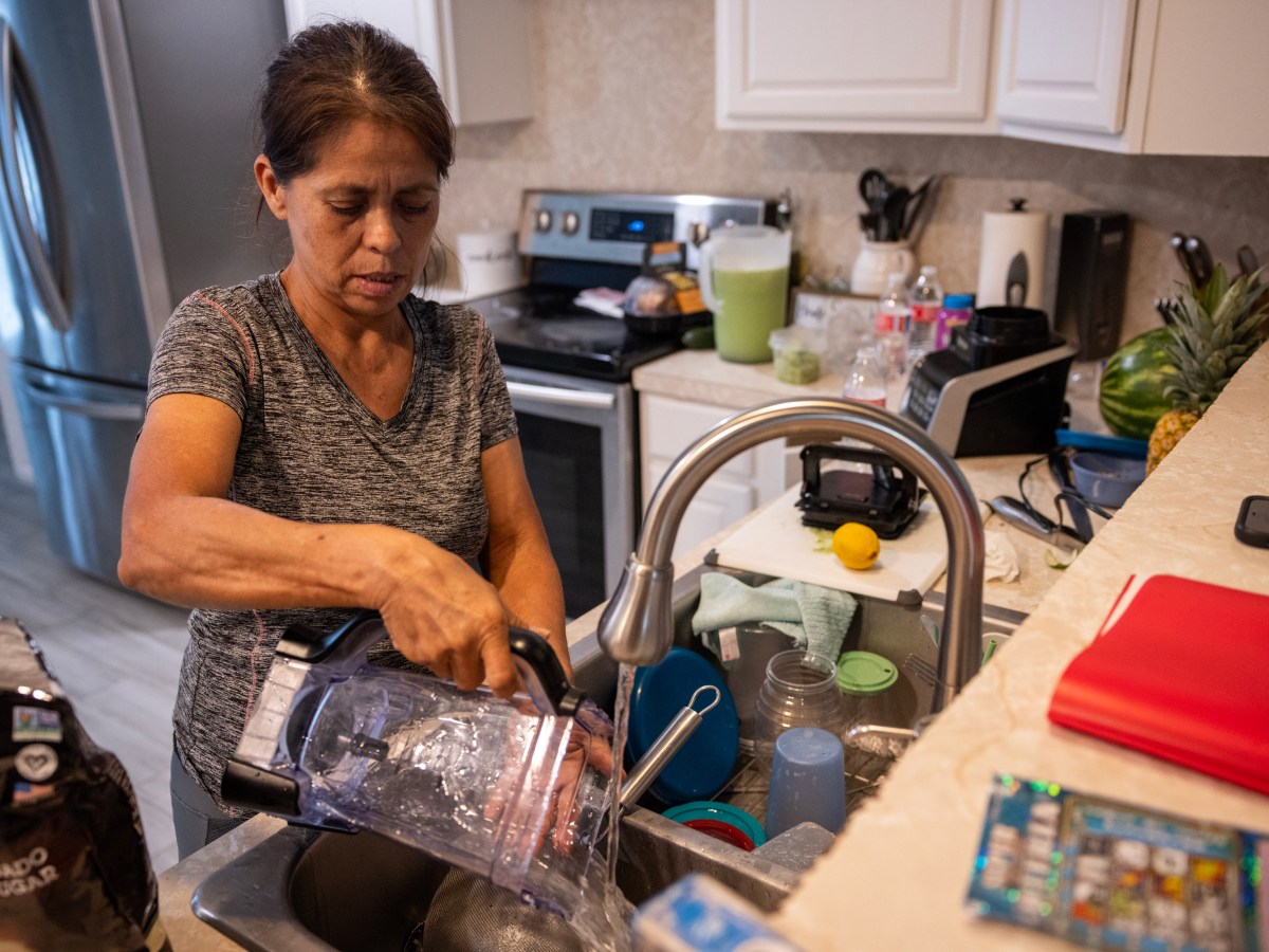Irma Acosta washes a blender as she cooks dinner at her son’s home, in Fresno, Texas