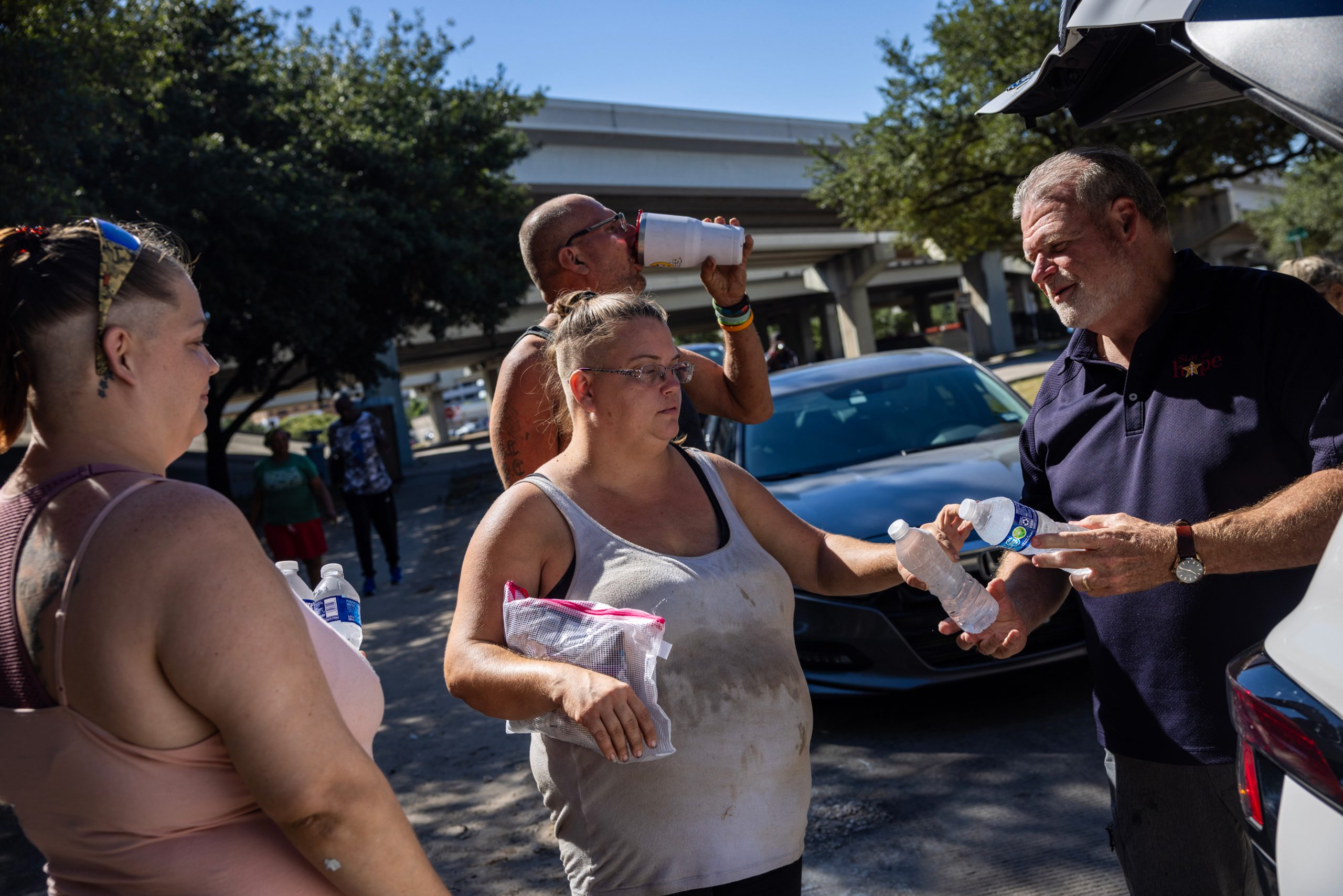 Ray Walker, outreach coordinator with Star of Hope Men's Development Center, hands out water bottles and food