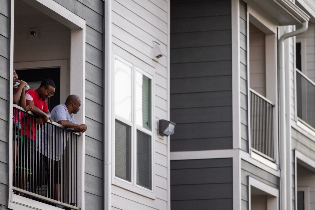 Onlookers watch law enforcement officers near a house where a suspected gunman had barricaded himself in northeast Harris County.
