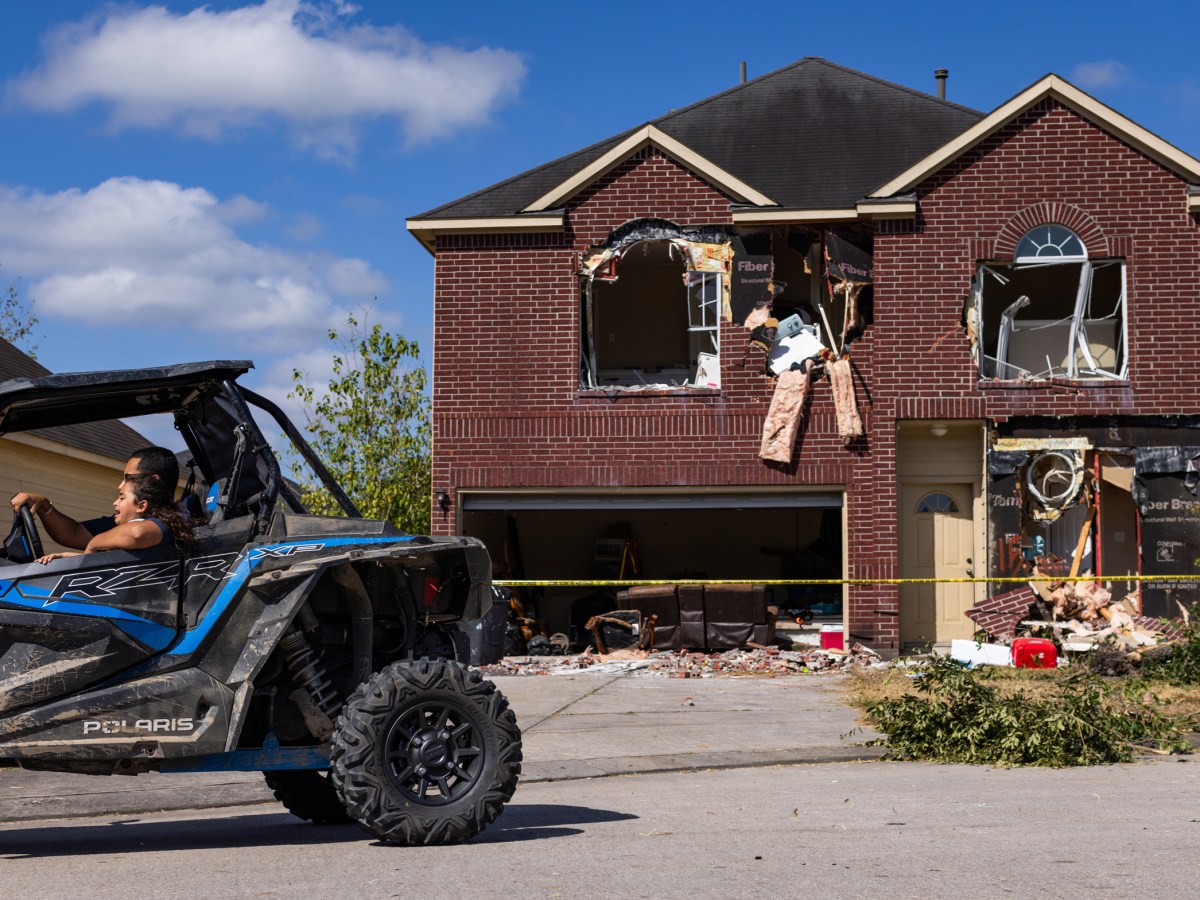 Onlookers drive by a house in northeast Harris County, Friday, Aug. 18, 2023, in Humble where Terran Green, the wanted suspect accused of shooting three police officers over a 24-hour period was barricaded Thursday.