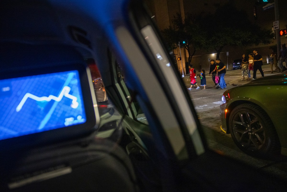 People pass by as a Cruise vehicle waits at a stop light during a ride through downtown Houston