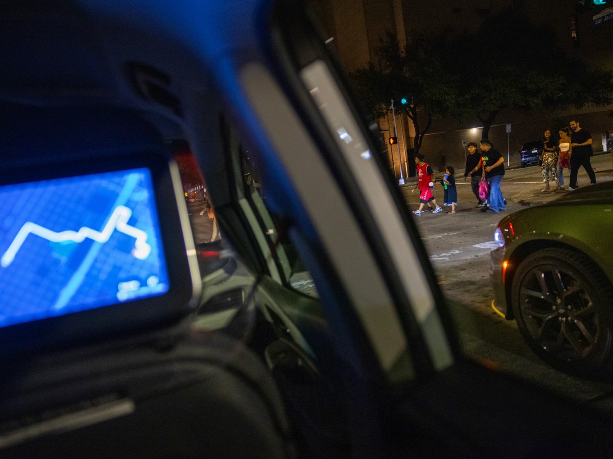 People pass by as a Cruise vehicle waits at a stop light during a ride through downtown Houston