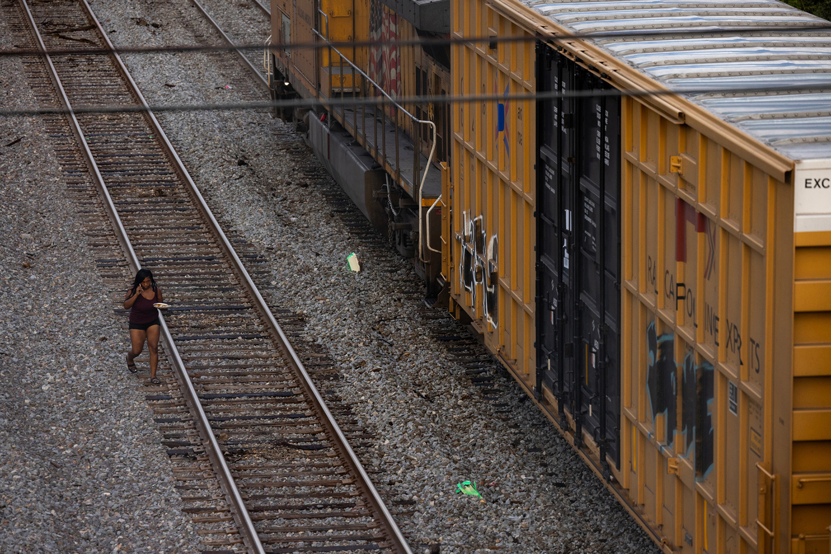 A woman walks along the train tracks to cross as a Union Pacific train is halted blocking an intersection,