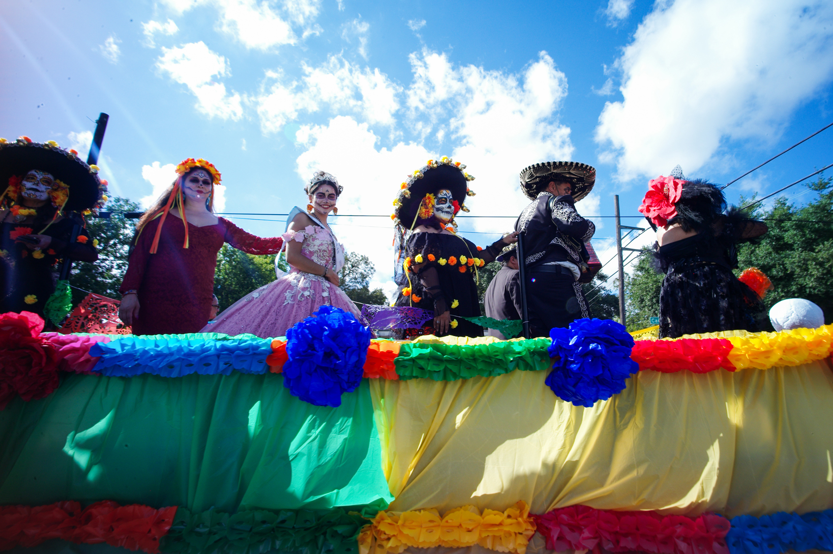Men and women stand on the Gabby’s Party Hall float during the Dia de los Muertos parade