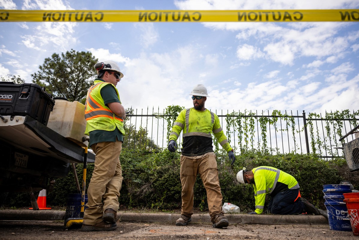 Contractors install a device used to help measure the level of fumes coming from chemical plumes underground on Nov. 9 in Houston.