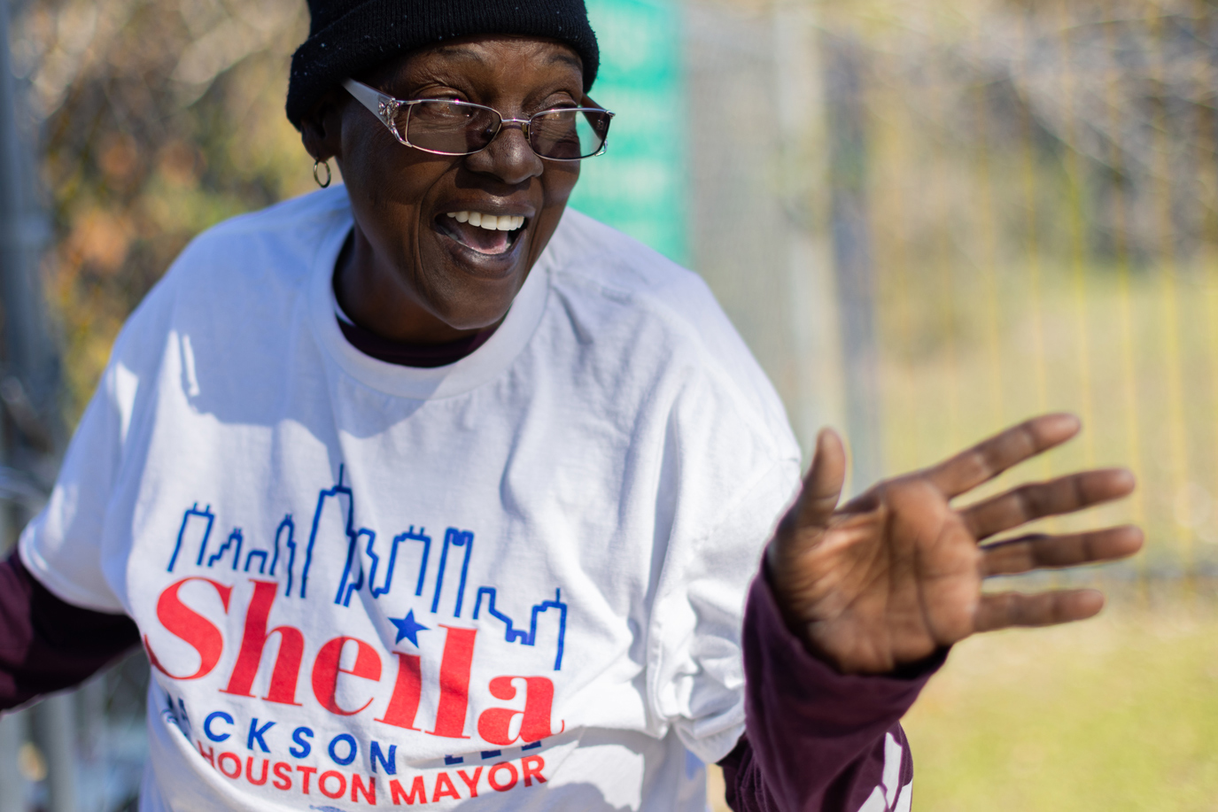 A candidate supporter and campaign worker in Houston hypes voters driving to a polling place.