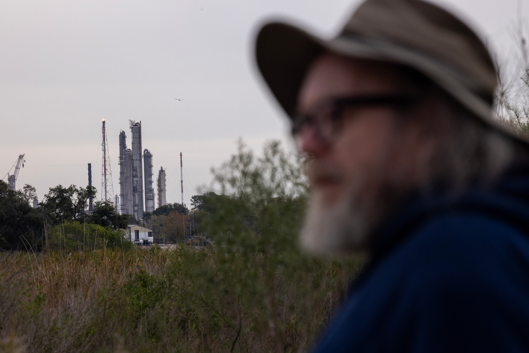 A bird flies past ExxonMobil Chemical - Baytown Technology as J.J. Hitt looks at the sky at the near Baytown Nature Center