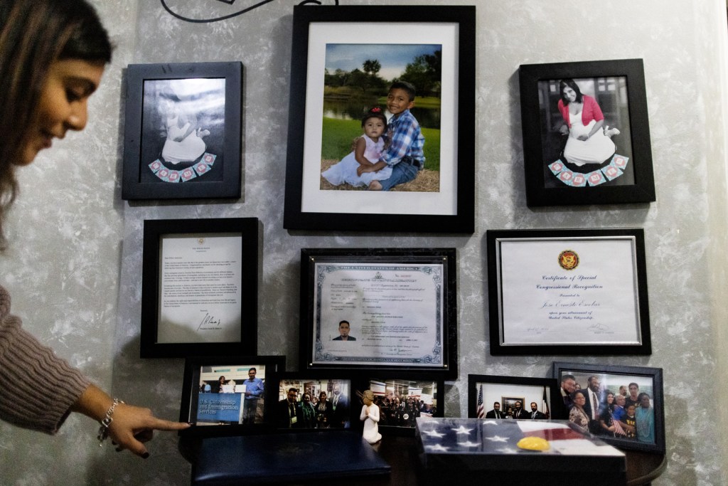 Rose Escobar points at a collection of photos memorializing  the return of her husband, Jose, after being deported to El Salvador in 2017, returning home to Texas over two years after, and eventually becoming a United States citizen in 2022. 