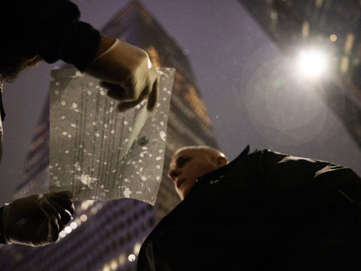 Houston Police Officer Jeff Richard gives a ticket to John Locke, Food Not Bombs volunteer, for setting up a tent to shelter from the rain as they serve people free dinners outside the Houston Public Library- Central Library, Wednesday, Jan. 24, 2024, in Houston.