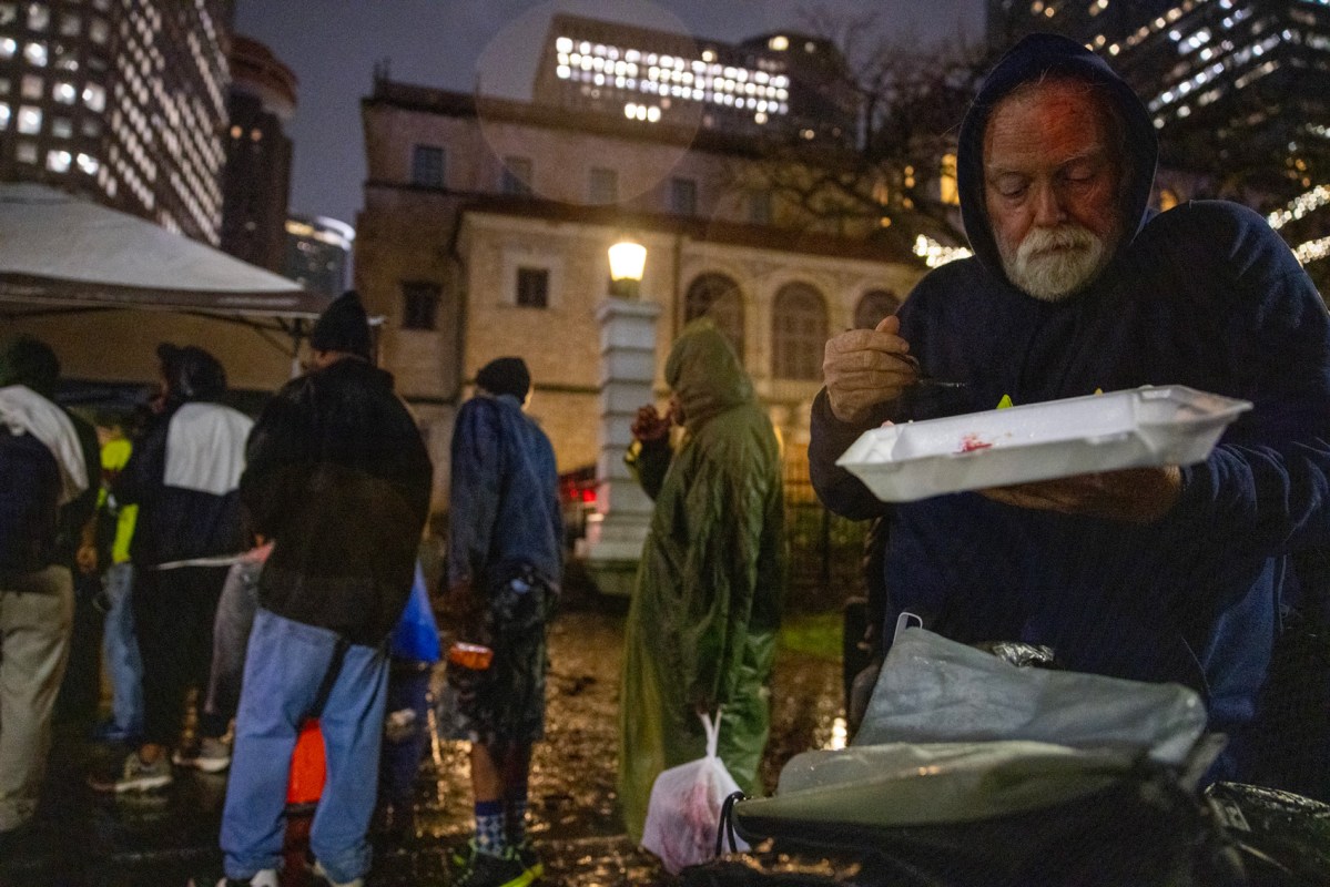 Robert Goolsby, 64, eats his dinner provided by Food Not Bombs as it rains outside the Houston Public Library- Central Library, Wednesday, Jan. 24, 2024, in Houston.