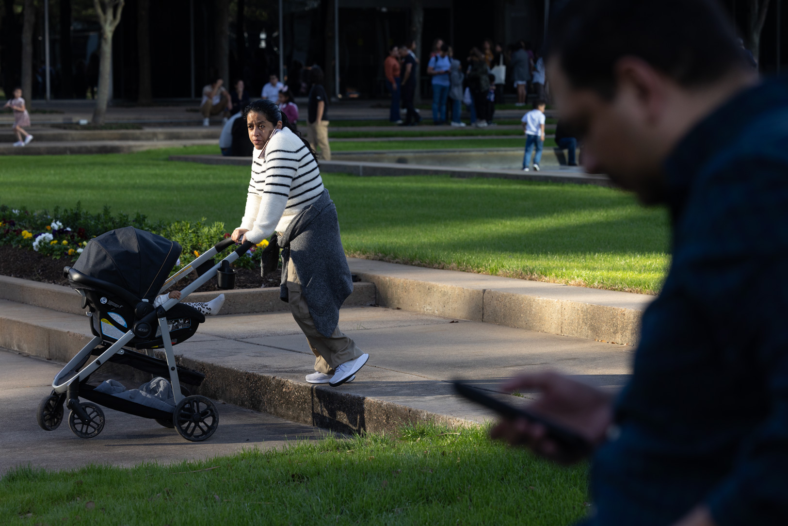 A woman talks on the phone as she walks out of a family reunification area with a baby outside Lifetime Fitness after a reported shooting at Lakewood Church, Sunday, Feb. 11, 2024, in Houston.