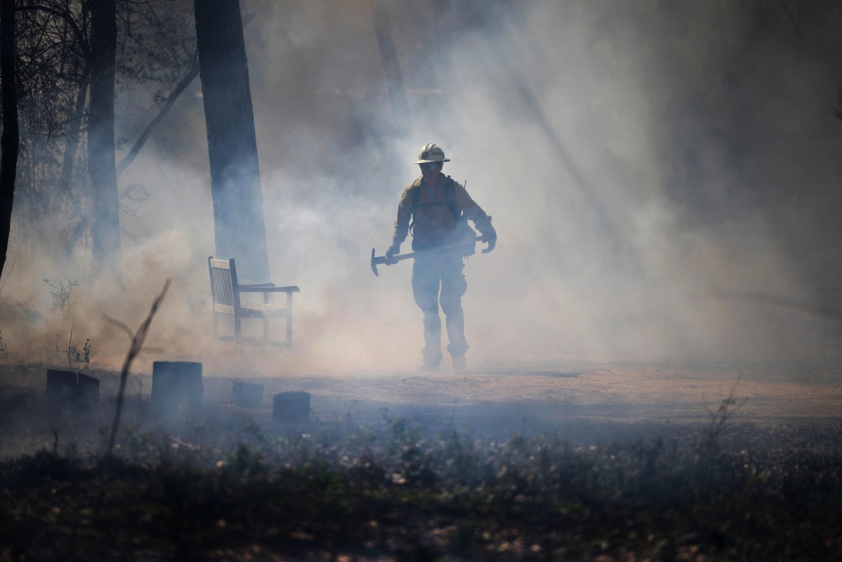 A firefighter walks through smoke during a controlled burn of a section of the Houston Arboretum & Nature Center, Wednesday, Feb. 21, 2024, in Houston.