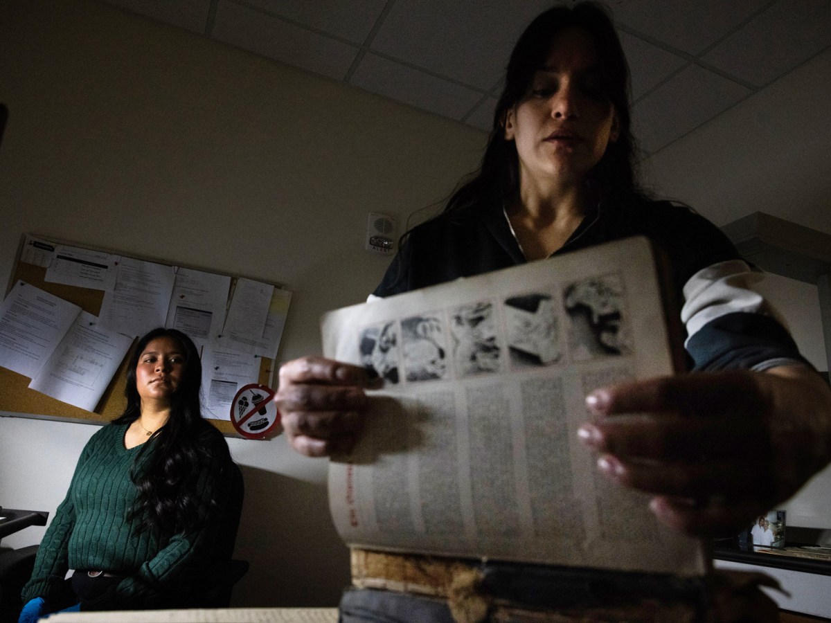 Perla Ortiz, graduate research assistant, at left, watches as Mikaela Selley, archivist and program manager, goes through a family bible donated by A. John Castillo at Arte Público Press,