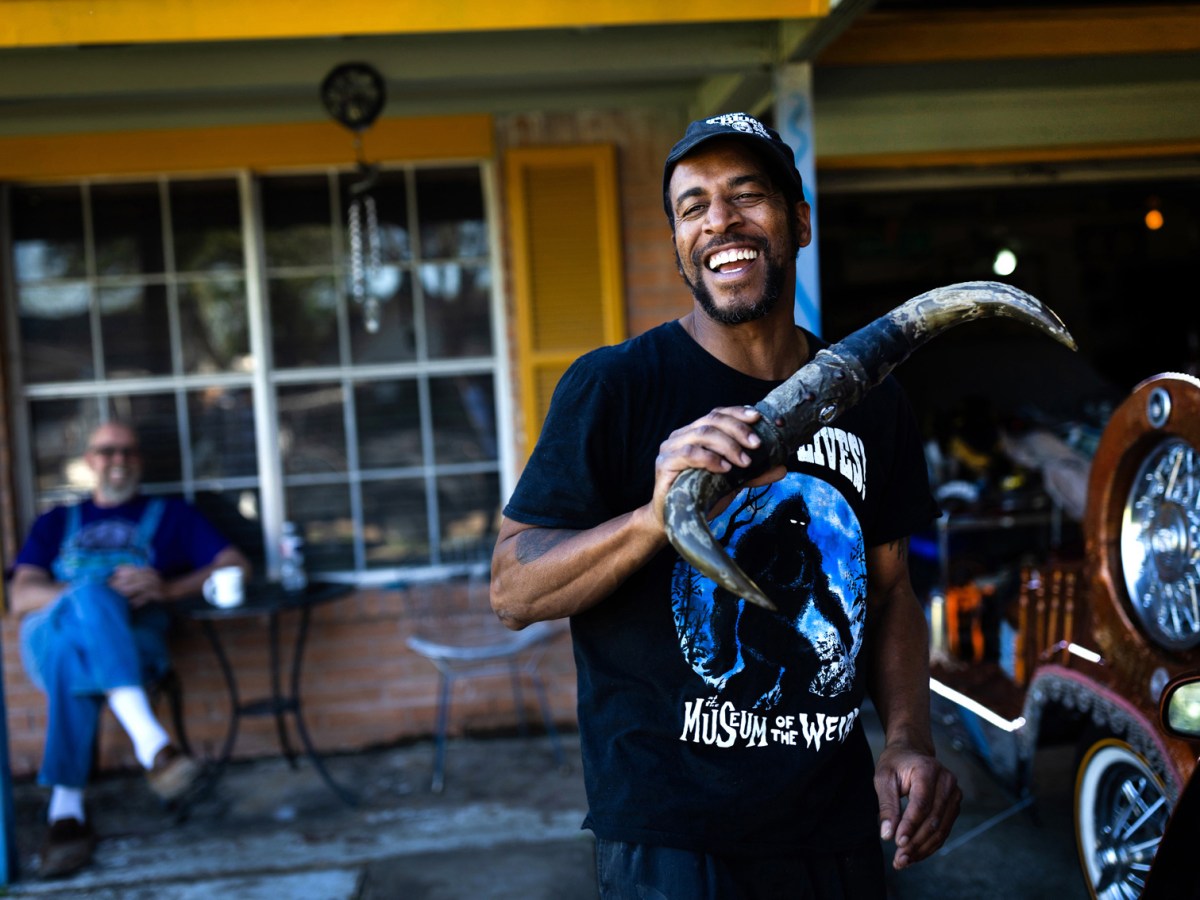 Houston-based artist and educator Rickey Polidore, 47, jokes around with cattle horns as he searches for the right spot to add to The Hermesillac, a 1994 Cadillac Fleetwood Brougham at his home in southwest Houston on Thursday, April 4, 2024, ahead of The Houston Art Car Parade on April 13.