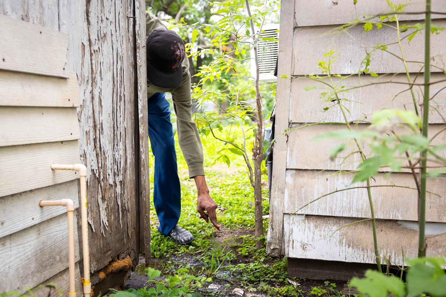 Mal Berth points to where he sees raw sewage pooling on his property outside his home on Monday.