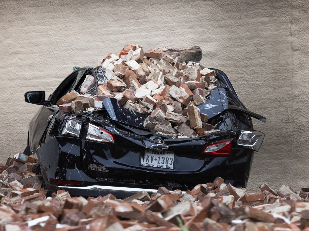 A car roof is flattened after bricks from a partially collapsed wall of Conejo Malo fell on it in downtown, Friday, May 17, 2024, in Houston.