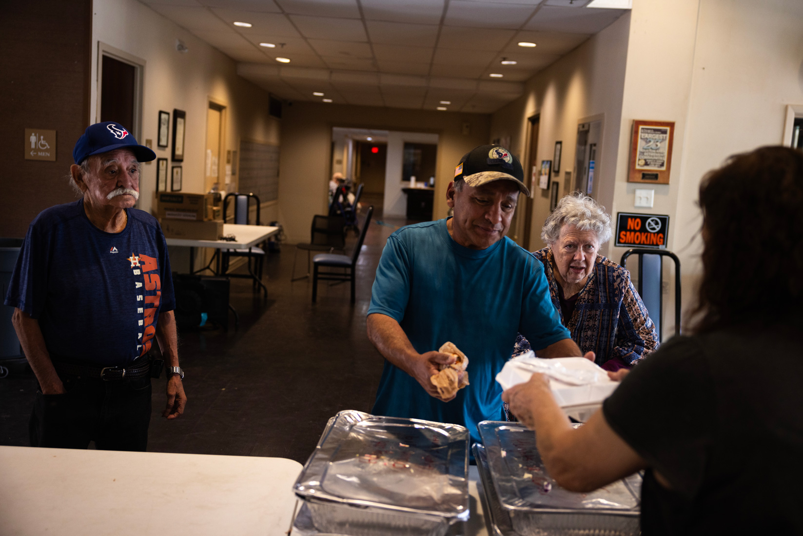 From left, Paul Cortez Sr., Paul Cortez Jr., and Sandra Lord, 83, line up to receive donated food at Houston Heights Tower, Sunday, May 19, 2024, in Houston.