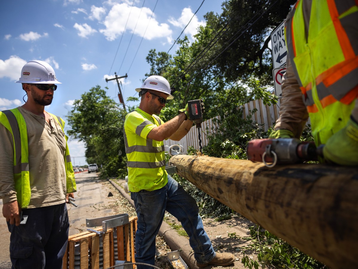 A crew works on installing a new utility pole on Durham Drive, Sunday, May 19, 2024, in Houston after a powerful windstorm swept through the city.
