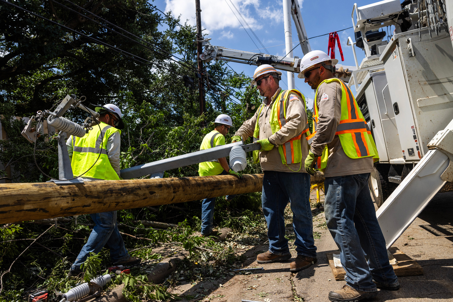 A crew works on installing a new utility pole on Durham Drive, Sunday, May 19, 2024, in Houston after a powerful windstorm swept through the city.