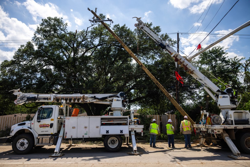A crew works on installing a new utility pole on Durham Drive, Sunday, May 19, 2024, in Houston after a powerful windstorm swept through the city.