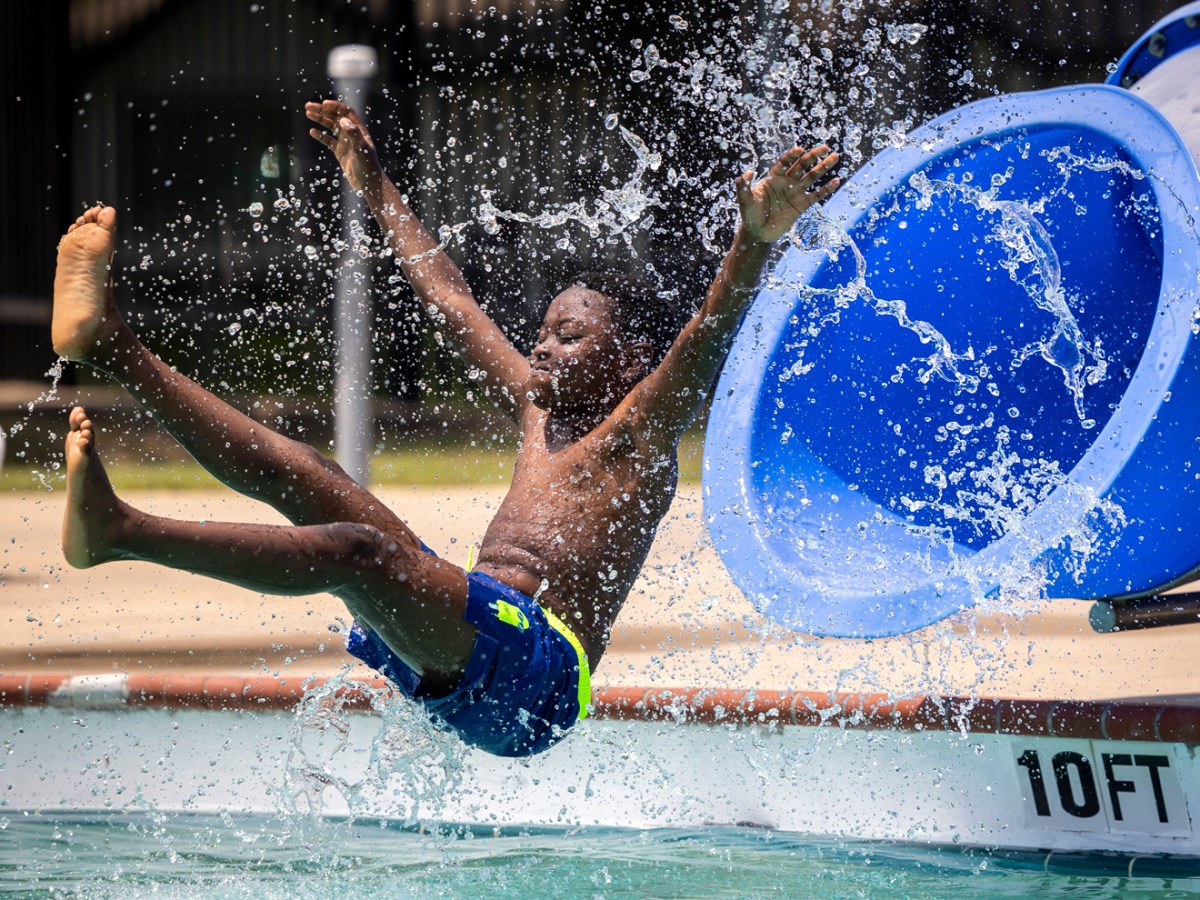 Adil Kone, 7, flies out of a waterslide during the grand re-opening of Westbury Pool on Saturday, May 25, 2024, in Houston.