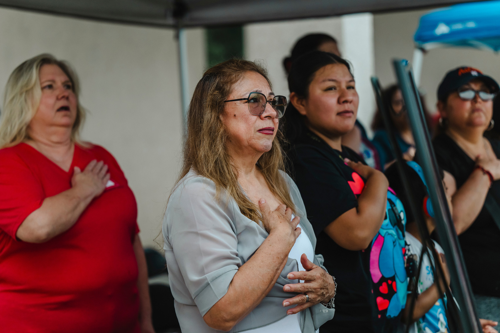 Carolina Pérez holds her hand over her heart as she listens to the National Anthem being sung, alongside fellow Gold Star families, during the Memorial Day ceremony at the Houston National Cemetery on May 27, 2024. Ms. Pérez oldest son, Jesús Antonio Leon, was killed in Iraq in 2005. “He was very loved and it hurts for him to be gone but he is always in our hearts,” she said. 