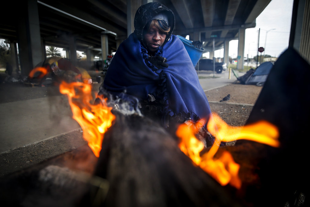 Tony Sampson, who received a blanket from Star of Hope's Love in Action van, tries to warm up by a fire under the Eastex Freeway as temperatures hover in the 30s Tuesday, Jan. 2, 2018, in Houston. Plunging overnight temperatures in Texas brought rare snow flurries as far south as Austin, and accidents racked up on icy roads across the state.
