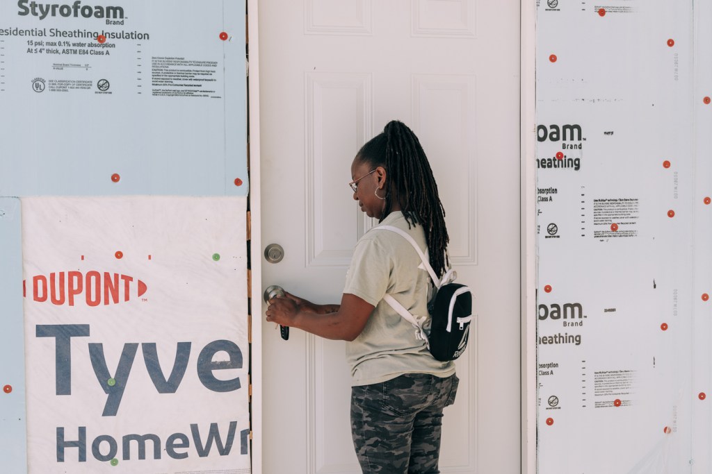 A person locks a door of a house in construction.