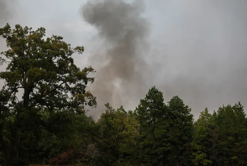 Heavy smoke from a large wildfire is seen rising from behind trees on Sept. 2, 2023, near Huntsville in Walker County. Texas fire departments are stretched thin as they continue fighting fires this year.