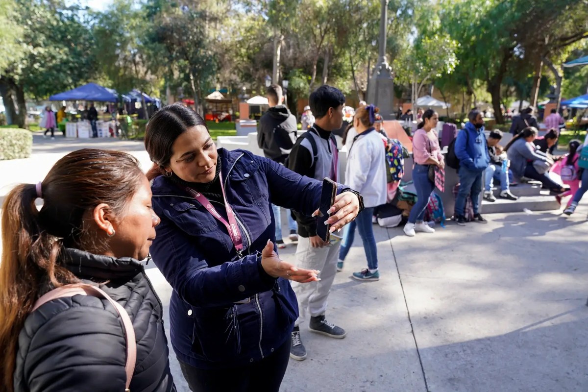 Migrants get help with the CPBOne app from workers in the city of Tijuana, Mexico Tuesday, Jan. 24, 2023, in Tijuana, Mexico. A mobile app for migrants to seek asylum in the United States has been oversaturated since it was introduced this month in one of several major changes to the government's response to unprecedented migration flows.